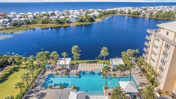 A resort with a large pool, palm trees, and a view of the ocean.