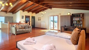 A spacious room with a large bed, a sofa, a desk, and a bookshelf. - Spacious Family Villa near to amenities with pool (Rethymno)