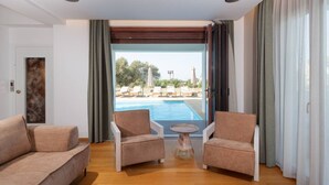 A room with a pool view, two armchairs, a small table, and a door with a frosted glass panel. - Spacious Family Villa near to amenities with pool (Rethymno)