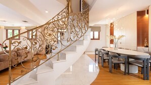 A modern interior with a curved staircase, a dining area, and a living space. - Spacious Family Villa near to amenities with pool (Rethymno)