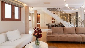 A modern living room with a sofa, a round coffee table, and a vase of flowers. - Spacious Family Villa near to amenities with pool (Rethymno)