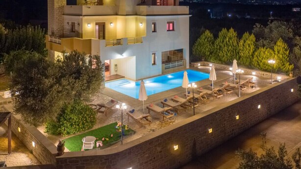 A modern villa with a swimming pool, outdoor seating, and a stone wall surrounding the property. - Spacious Family Villa near to amenities with pool (Rethymno)