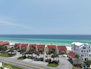 A coastal hotel with multiple buildings, a parking lot, and a view of the ocean.