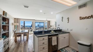 Una cocina moderna con una isla grande, armarios blancos y vistas al exterior.