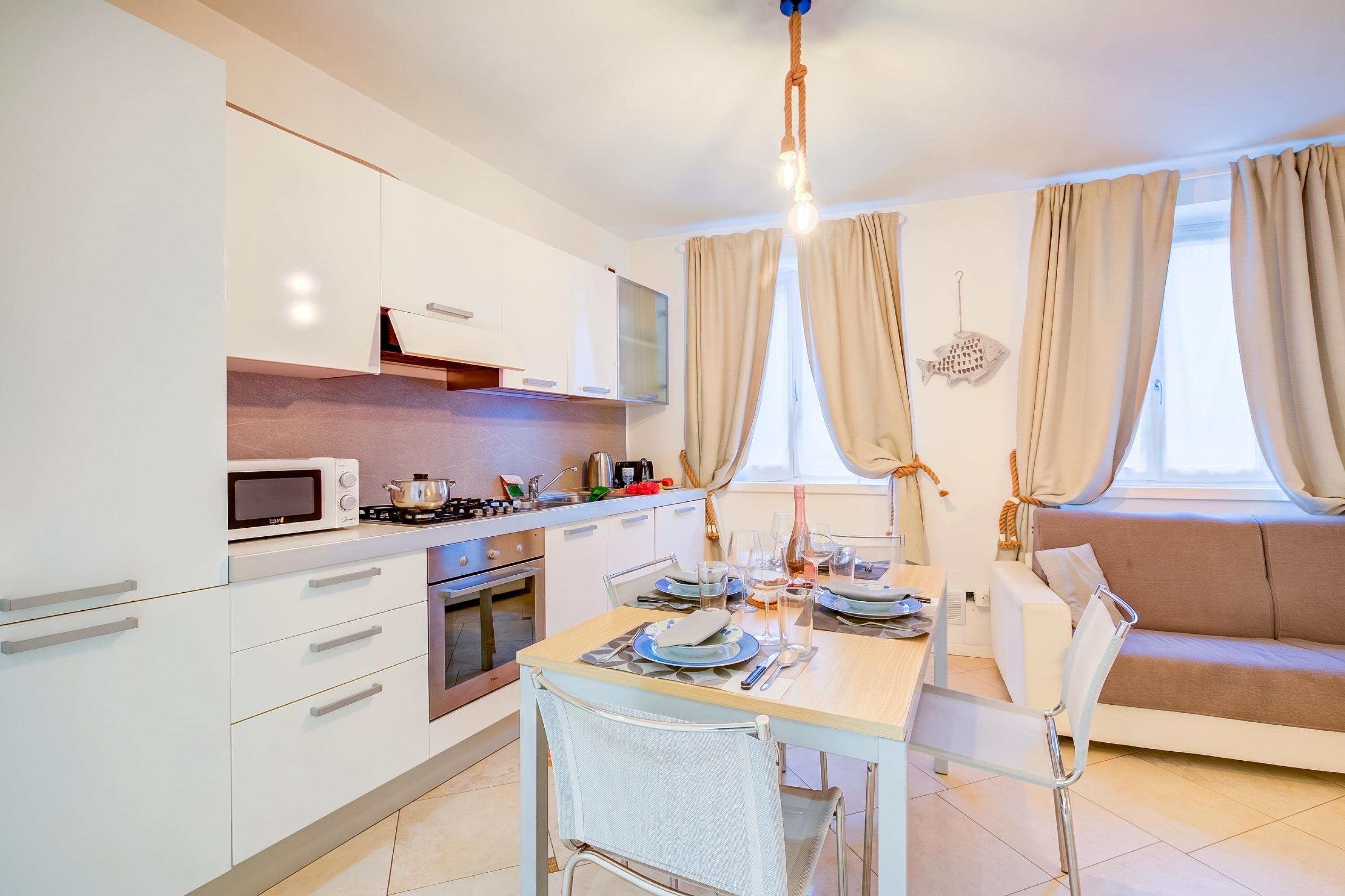 A modern kitchen with white cabinets, a microwave, and a dining area with a table set for two.