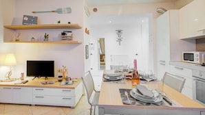 Une cuisine moderne avec des meubles blancs, un four à micro-ondes et un coin repas avec une table mise pour deux personnes.