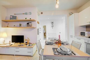 A modern kitchen with white cabinets, a microwave, and a dining area with a table set for two.