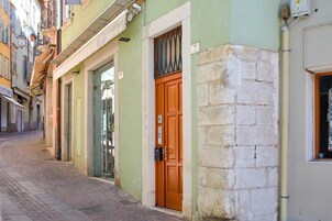 A narrow street with buildings, a green door, and a brick wall.