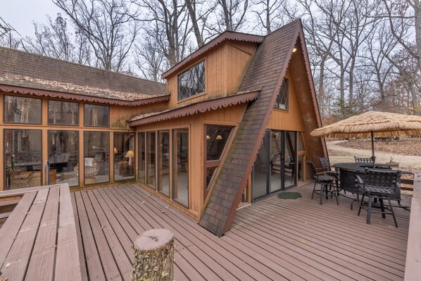 A wooden cabin with a sloped roof, large windows, and a deck with outdoor furniture.