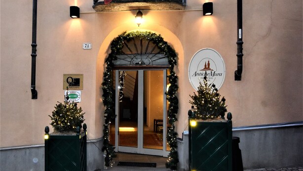 Un edificio con balcón, banderas, un árbol de Navidad y un letrero que dice "Antico Mura".