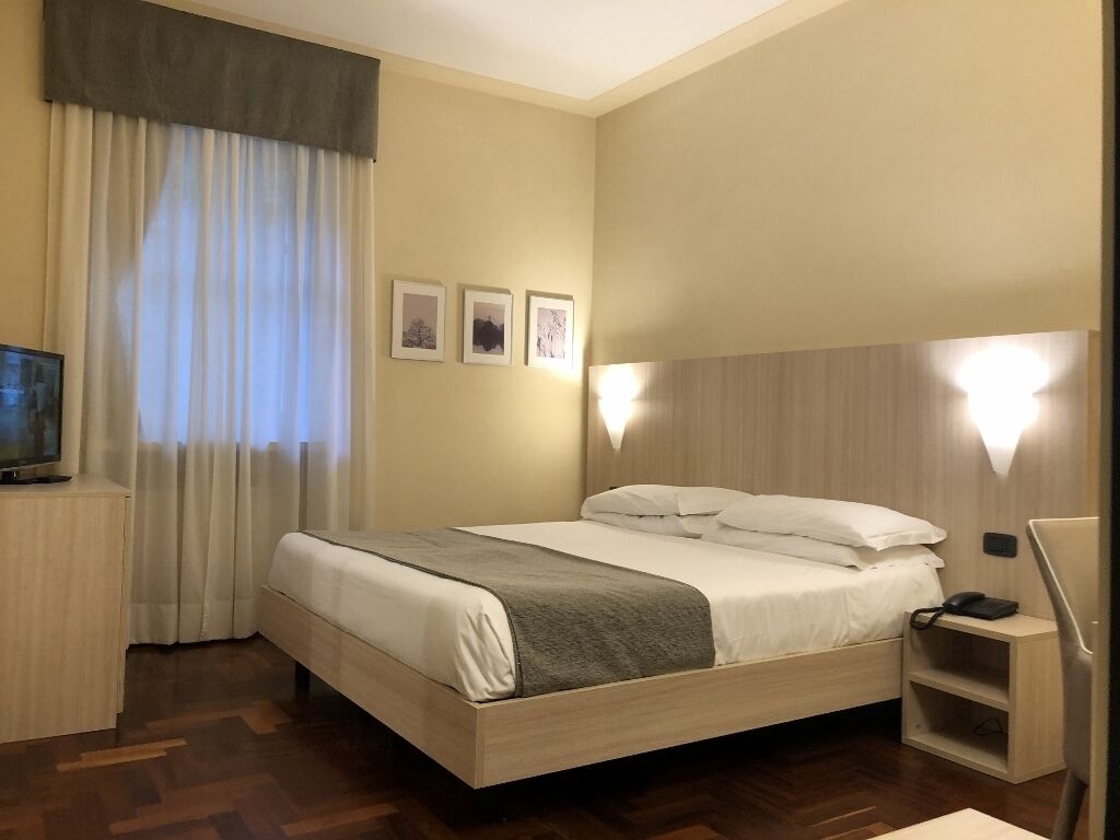 Ein Hotelzimmer mit Bett, Fernseher, Schreibtisch und Stuhl.