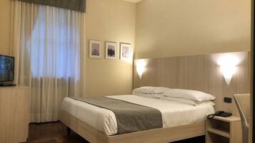 Ein Hotelzimmer mit Bett, Fernseher, Schreibtisch und Stuhl.