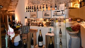Un interior con techo de ladrillo, botellas de vino en estanterías y una pared de piedra.