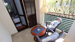 Ein Balkon mit Stuhl, Tisch und Blick auf einen Garten.
