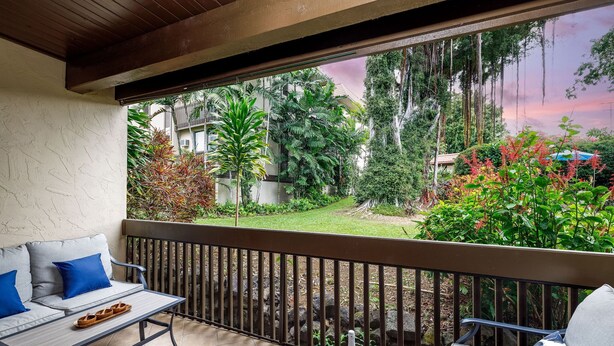 Ein Balkon mit einer Couch, einem Tisch und einer Weinflasche.