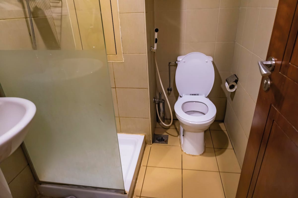 A small bathroom with a toilet, a sink, and a shower area.