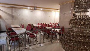 A conference room with red chairs, a large chandelier, and a white table. - Diyafa Al Mukhtara Hotel (Madinah)