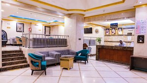 A hotel lobby with a reception desk, seating area, and a staircase leading to an upper level. - Diyafa Al Mukhtara Hotel (Madinah)