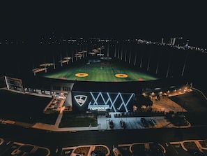 Un estadio con césped verde, un logotipo iluminado de gran tamaño y un área de estacionamiento.