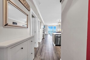 A hallway leading to a kitchen with a dining area and a view of the outdoors.