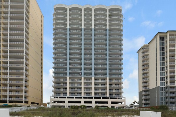 A multi-story hotel with a curved facade, balconies, and a parking structure at the base.