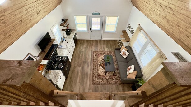 A spacious loft-style living area with a kitchen, a sofa, and a dining table. - Bass Cabin: Arcade, Inflatables, Fishing & More! (Guntersville)