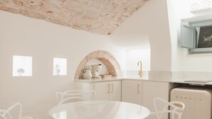 Une cuisine moderne avec des meubles blancs, une arche en marbre et une table blanche accompagnée de chaises.