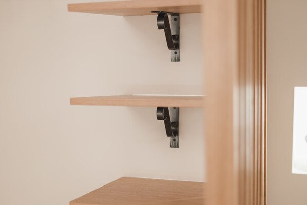 A minimalist room with two wooden shelves mounted on a white wall.