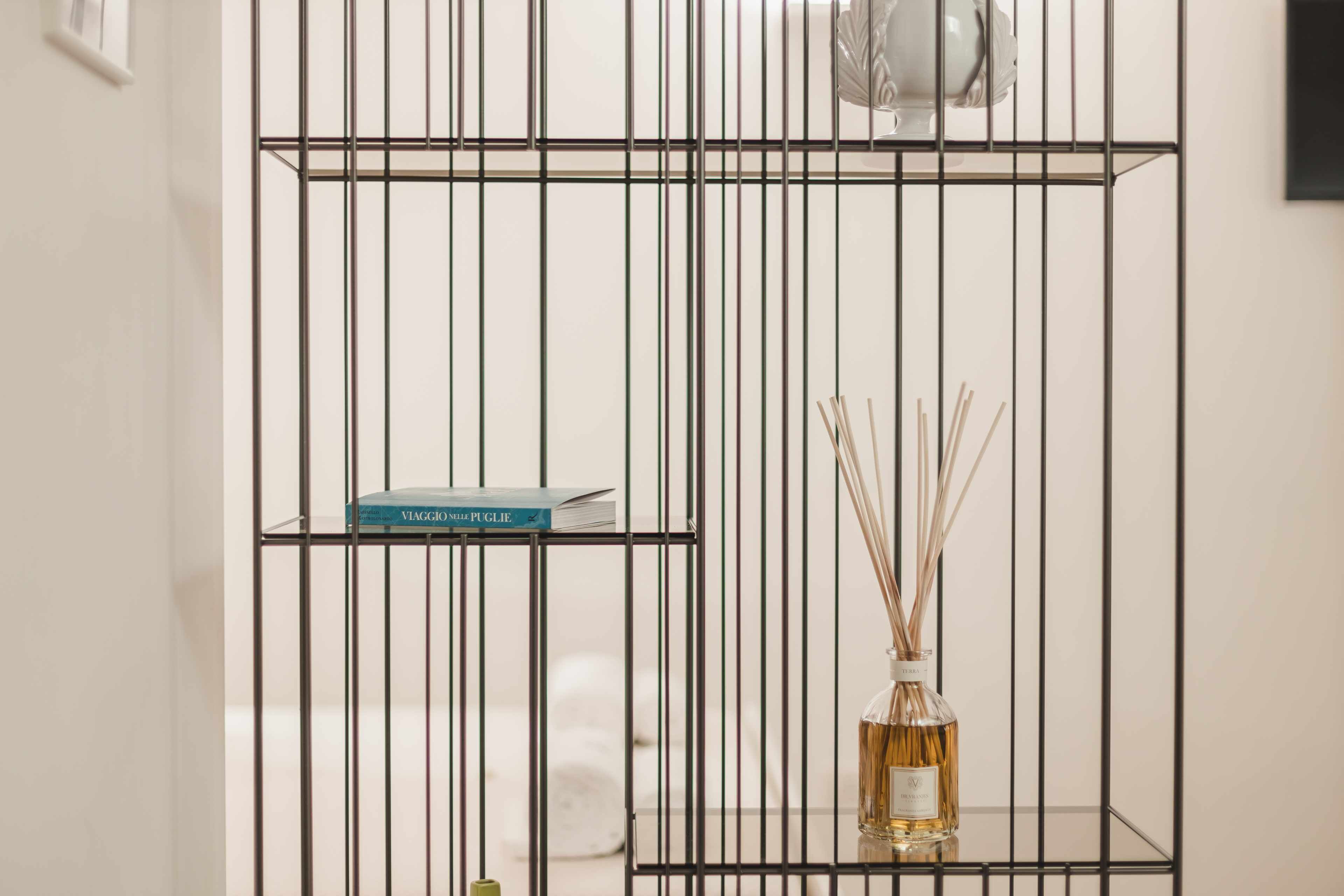 A metal shelf unit with a book and a bottle of reed diffuser.