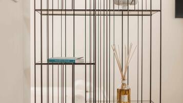 A metal shelf unit with a book and a bottle of reed diffuser.