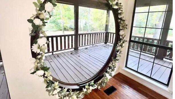 A circular mirror with a wooden frame and floral decoration, mounted on a wall.