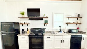 Una cocina moderna con armarios blancos, una estufa negra, un refrigerador negro, un microondas y un lavavajillas.