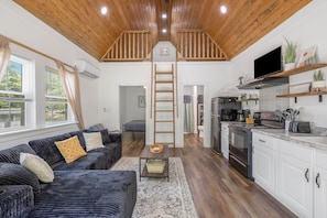 Un vaste espace de vie avec une chambre en mezzanine, une cuisine équipée d’appareils modernes et une vue sur l’extérieur.