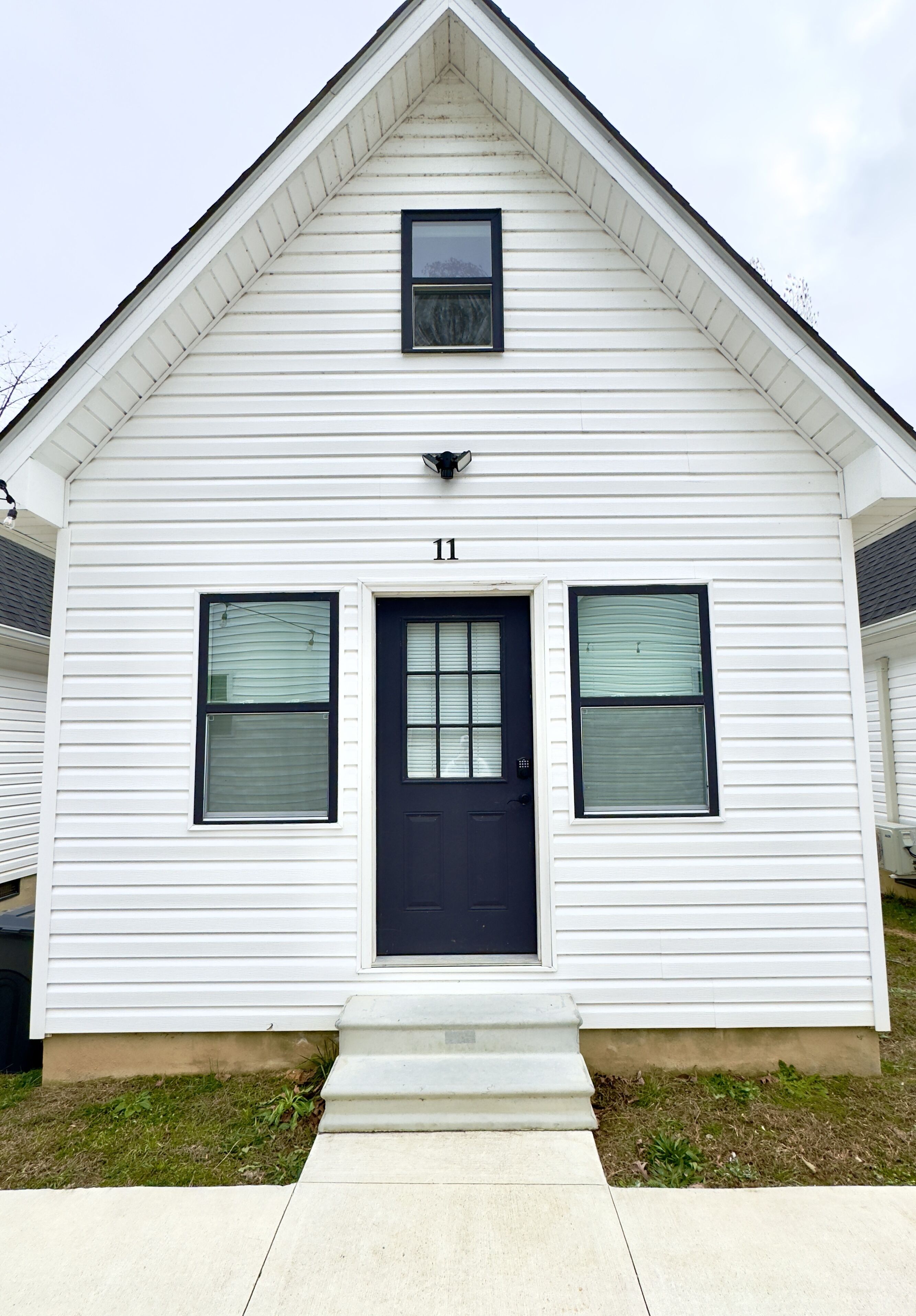 A white two-story house with a black front door, numbered 11, and two windows on the first floor.