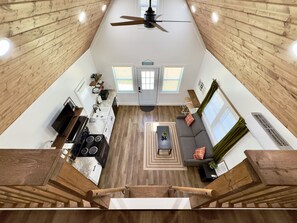 A spacious living area with a kitchen, dining table, and a sofa. - Blue Gill Cabin: Arcade, Fishing, Kayaks, Cornhole (Guntersville)