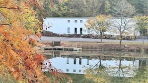 A building with a white exterior, a dock, and a pond reflecting the structure.