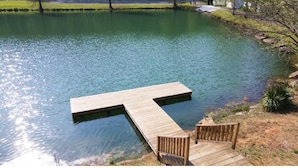 Un muelle de madera se extiende sobre aguas tranquilas, con un banco y una silla allí.