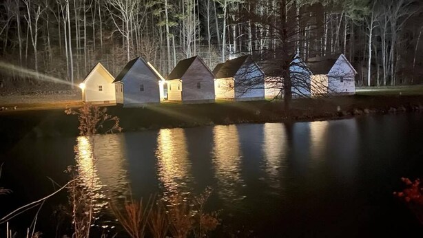 Cabañas en fila a orillas de un lago, con reflejos en el agua.