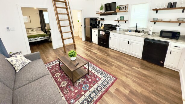 Eine moderne Wohnung mit Schlafgalerie, einer Küche mit weißen Schränken und einem Essbereich.