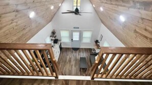 A high-ceilinged room with wooden walls and a central ceiling fan.
