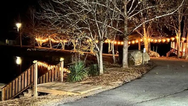 A pathway leading to a building with string lights and a wooden fence.