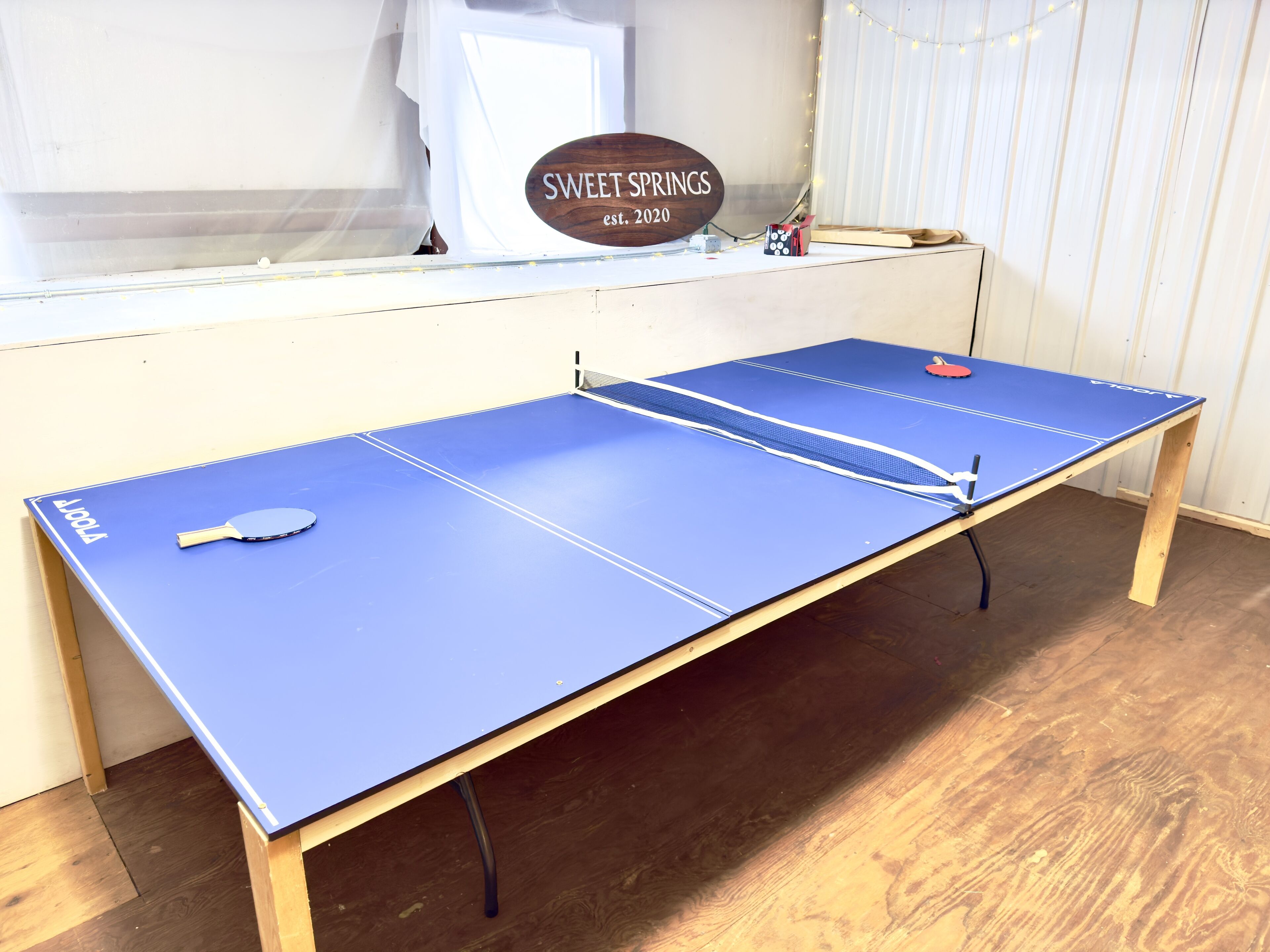 Ein Pingpongtisch mit blauer Tischplatte, ein Schläger und ein Ball.