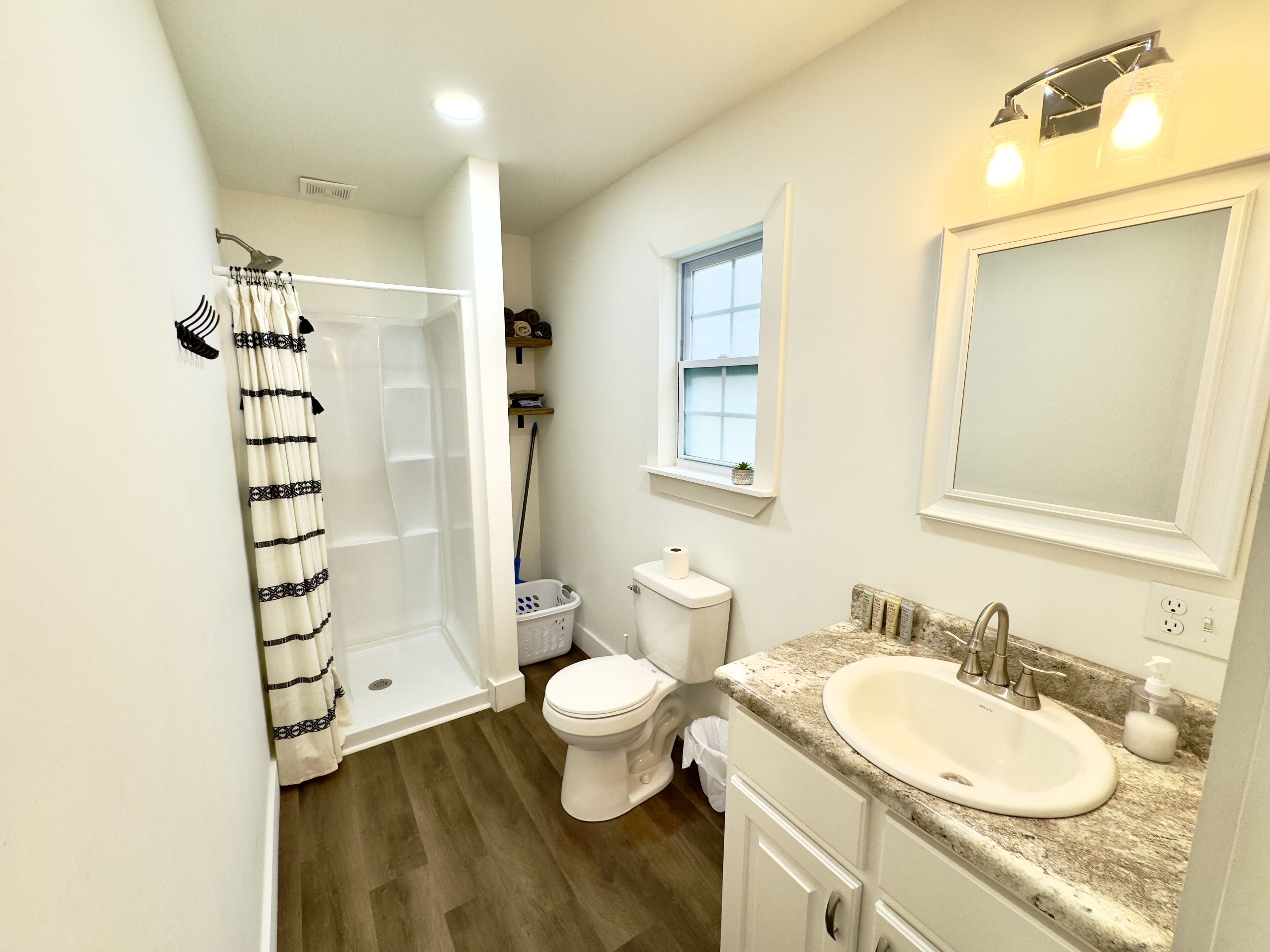 A bathroom with a shower, toilet, sink, and a window.
