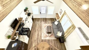 A spacious living area with a ceiling fan, a sofa, a coffee table, and a kitchen area with a stove and sink.