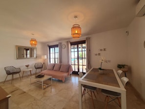 A spacious living area with a sofa, coffee table, dining table, and chairs. There are large windows with curtains, a mirror, and a clock on the wall. - Escape to Paradise:Villa Perla Nera – Your Oasis of Comfort and Serenity!
(Playa Blanca)