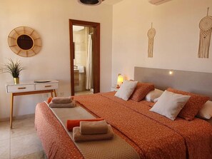 A bedroom with a large bed, a desk, a chair, a bedside table with a lamp, and a wall-mounted decorative item. - Escape to Paradise:Villa Perla Nera – Your Oasis of Comfort and Serenity!
(Playa Blanca)