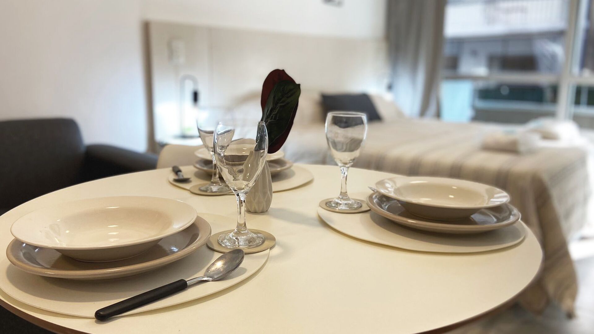 Una mesa de comedor ordenada con platos, vasos y cubiertos en una habitación de hotel.