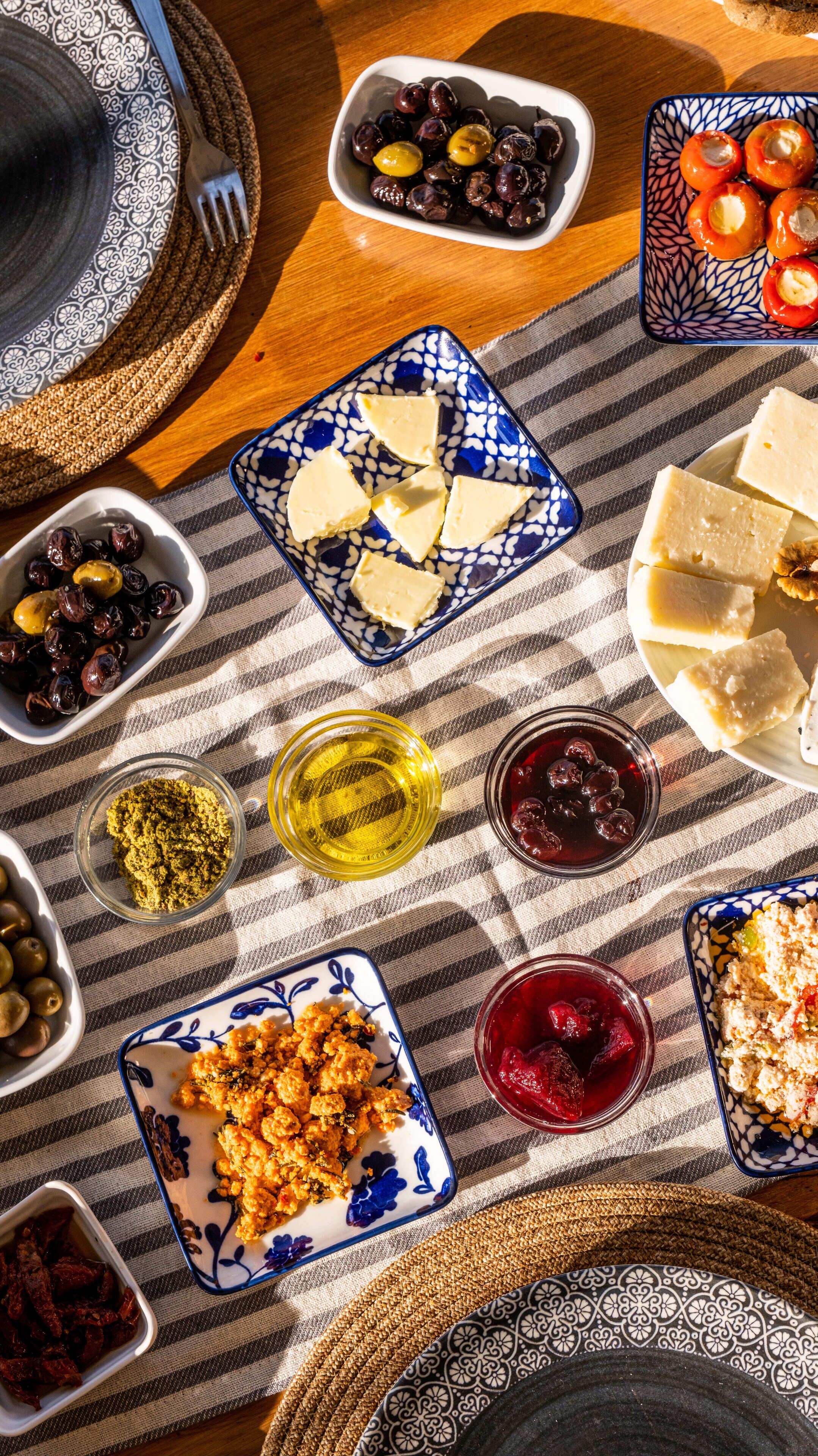 Uma mesa posta com diversos pratos, incluindo azeitonas, queijo e uma tigela de frutas secas.