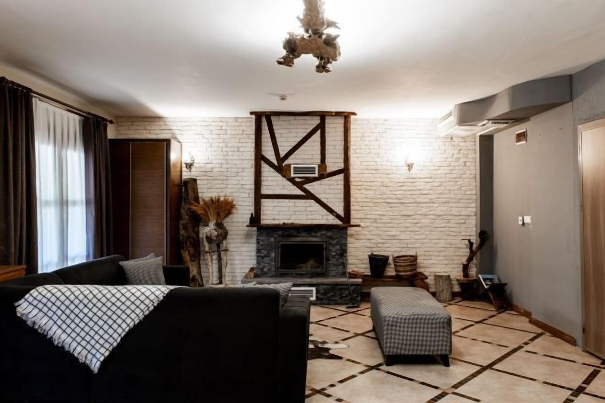 A living room with a fireplace, a sofa, a coffee table, and a patterned rug.
