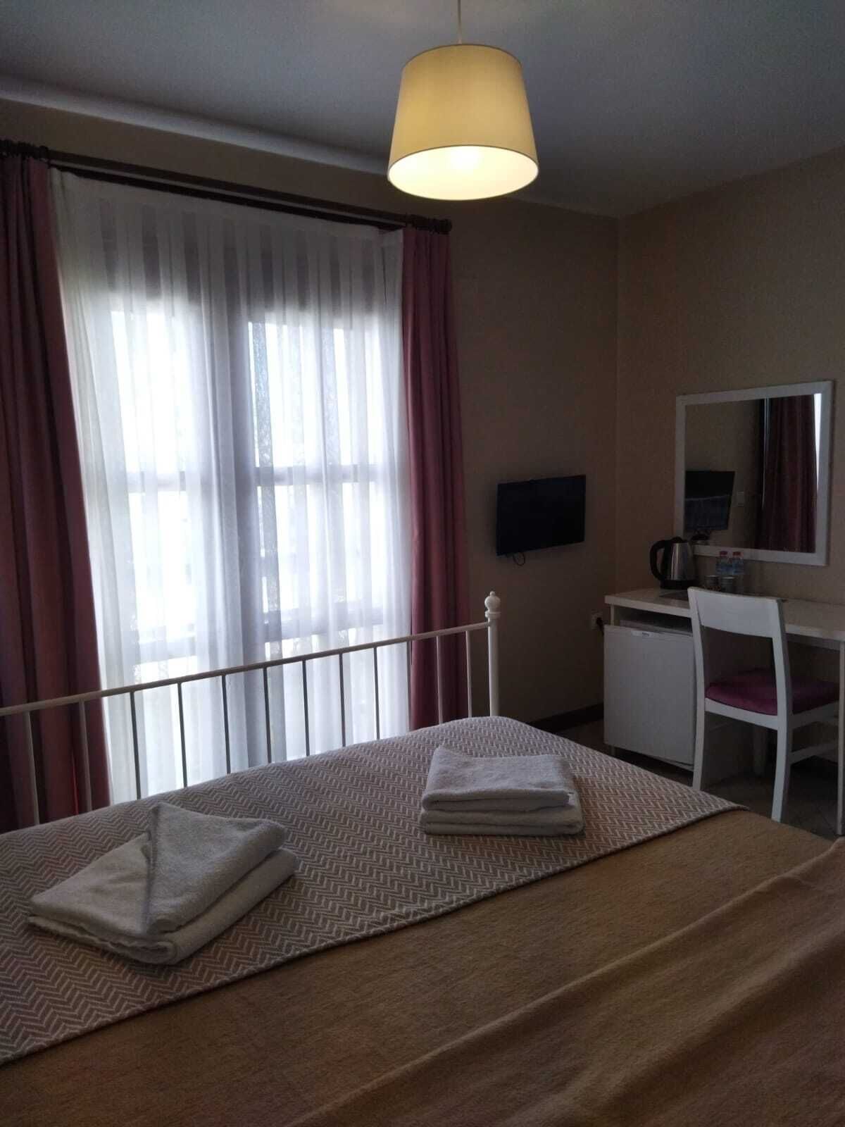A hotel room with a bed, a desk, a chair, a television, and a window with curtains.